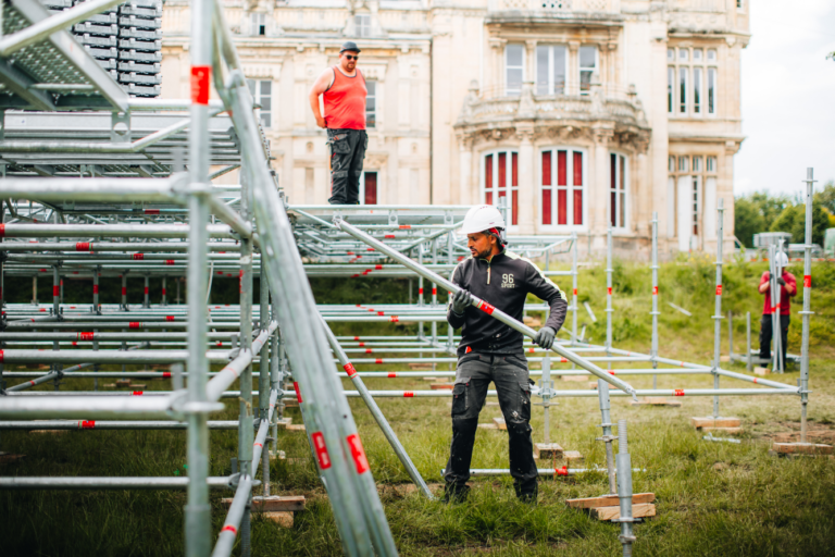 Ouvriers montant un échafaudage devant un château.