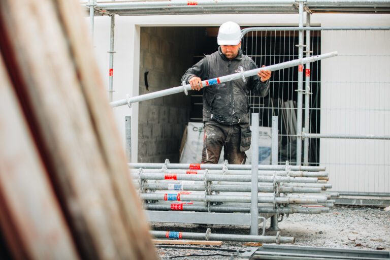 Ouvrier avec casque transporte tube sur chantier