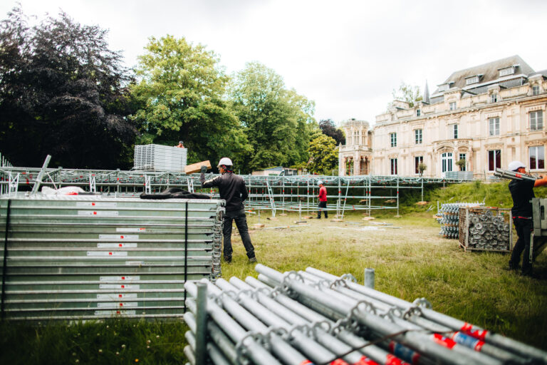 ouvriers montant une structure métallique devant château