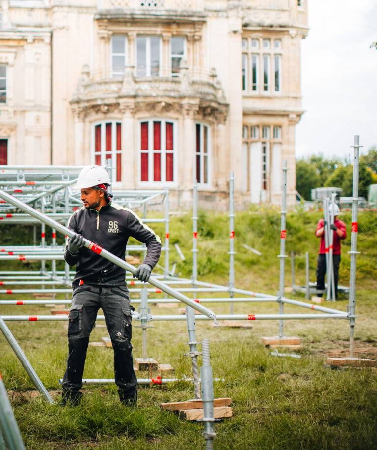 Ouvrier montant des échafaudages devant bâtiment historique